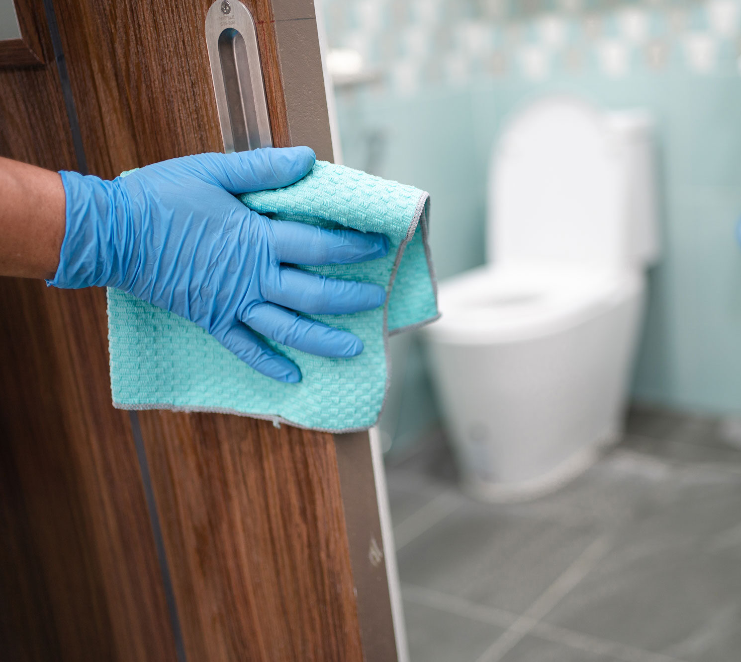 gloved hand wiping door handle of restroom